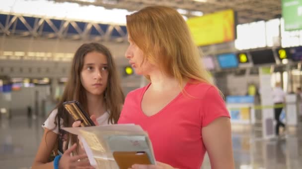 Le concept de tourisme, de loisirs et d'échange d'apprentissage. Femme et adolescente debout à l'aéroport à la billetterie pour l'enregistrement . — Video