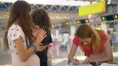 refakatsiz bir çocuğun taşınması kavramı. İki genç çocuklu bir kadın havaalanında belgeleri doldurur