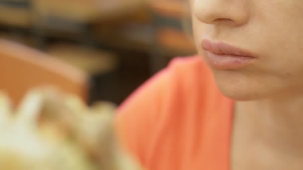 Zavřít. žena s kýchami na rtu jí hranolky a hamburger — Stock video