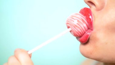 yakın çekim, kırmızı ruj ile kadın seksi dudaklar büyük pembe yuvarlak Lollipop emmek. alanı kopyalayın. mavi arka plan