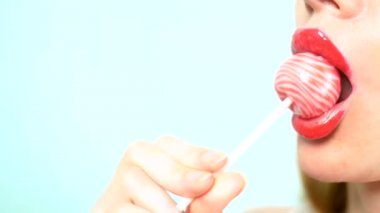yakın çekim, kırmızı ruj ile kadın seksi dudaklar büyük pembe yuvarlak Lollipop emmek. alanı kopyalayın. mavi arka plan