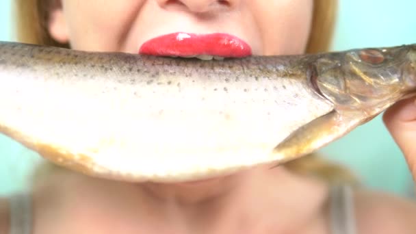 Zbliżenie. kobiece usta z czerwoną szminką z apetytem jeść duże surowe ryby. — Wideo stockowe