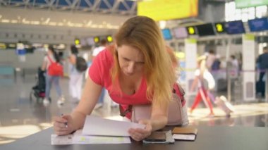 refakatsiz bir çocuğun taşınması kavramı. İki genç çocuklu bir kadın havaalanında belgeleri doldurur