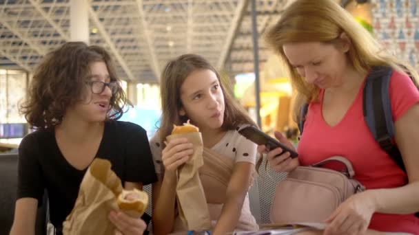 El concepto de turismo, recreación e intercambio de aprendizaje. Una mujer y dos adolescentes, un niño y una niña, en el aeropuerto, una mujer usando un teléfono inteligente — Vídeo de stock