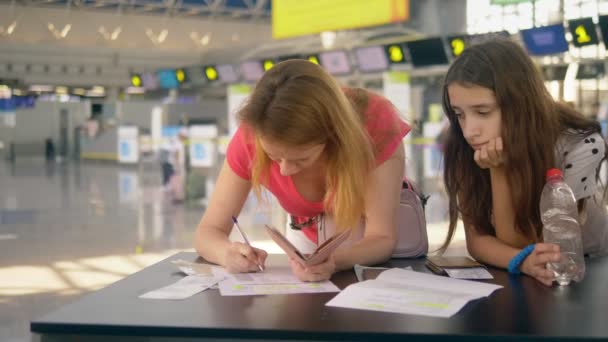 Concept van vervoer van een alleenreizende kind. Een vrouw met twee tiener kinderen vult documenten op de luchthaven — Stockvideo