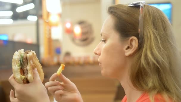 Att stänga. kvinna med herpes på läppen äter pommes frites och hamburgare — Stockvideo