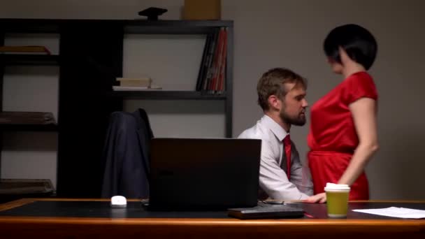 Pár, muž a žena v kanceláři, objetí a líbání. muž bere ženu a sedí na stole — Stock video