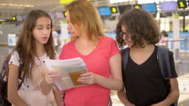 Turizm kavramı, tatil ve değişim eğitimi. Bir kadın ve iki genç, bir erkek ve bir kız, uçuş check-in için bilet ofisinde havaalanında ayakta.