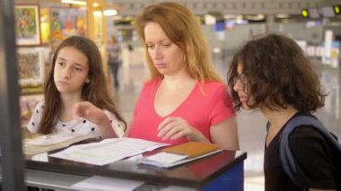 Turizm kavramı, tatil ve değişim eğitimi. Bir kadın ve iki genç, bir erkek ve bir kız, uçuş check-in için bilet ofisinde havaalanında ayakta.