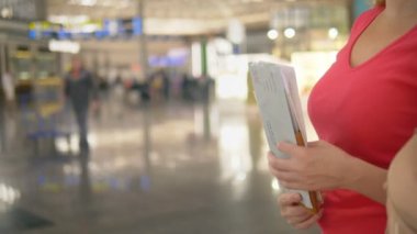 Turizm, rekreasyon kavramı. Bir kadın havaalanında check-in için bilet gişesinde duruyor, elinde belgeler tutuyor.