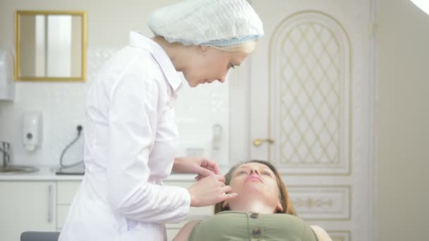 입술 주입, 입술의 볼륨을 증가시키는 동작. 미용전문의는 입술의 증가를위한 planimetric 성형술에 대한 환자 여성의 준비를 수행합니다. — 비디오