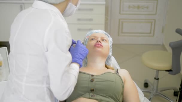 Obrys plastu. Kosmetolog vdělá botulotoxinu, aby zpevnit a vyhladit vrásky na kůži ženského obličeje. — Stock video
