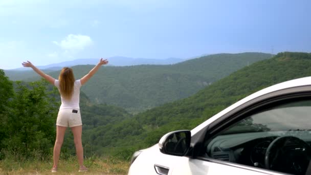 Verano viaje en coche a la libertad. mujer con las manos en alto, alegre y feliz contra el cielo azul y las montañas. Viaje de verano viajero concepto — Vídeo de stock