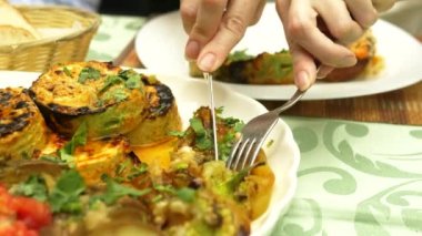 Bir restoranda ızgara sebze yakın çekim. Kadın bir bıçak ve çatal ızgara sebze ve şiş kebap ile yiyor