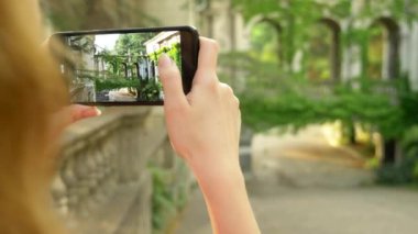Genç kadın eski bir kalenin bir sütun un telefonu ile fotoğraf çekmek