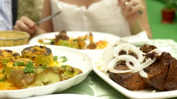 Legumes grelhados fechar em um restaurante. Mulher come com uma faca e garfo legumes grelhados e shish kebab — Vídeo de Stock