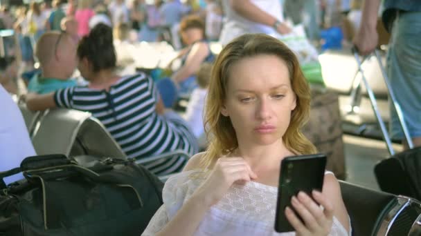 Mujer cansada usando smartphone en el aeropuerto. Aerolínea de pasajeros en el salón del aeropuerto está esperando un vuelo — Vídeos de Stock