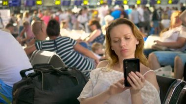 havaalanında akıllı telefon kullanan yorgun kadın. Havaalanı salonunda yolcu havayolu bir uçuş bekliyor