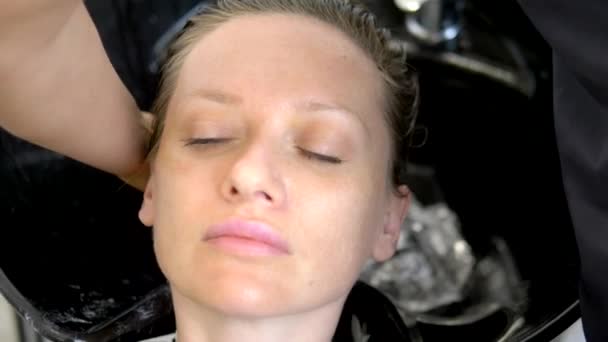 Close-up. o rosto de uma cliente feminina, cujo cabeleireiro mestre lava o cabelo num salão de beleza. Conceito de cabeleireiro no trabalho — Vídeo de Stock