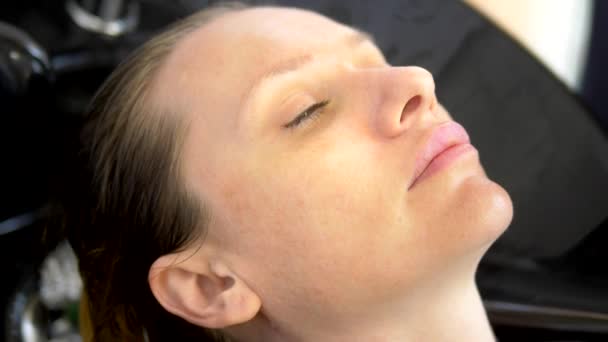 Close-up. het gezicht van een vrouwelijke cliënt, wiens Master Kapper haar haar in een schoonheidssalon wast. Kapper concept op het werk — Stockvideo