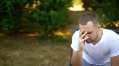 Depresif üzgün genç adam bir yaz parkında bir bankta tek başına oturuyor. kopyalama alanı