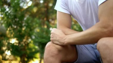 Depresif üzgün genç adam bir yaz parkında bir bankta tek başına oturuyor. kopyalama alanı