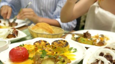 Bir restoranda ızgara sebze yakın çekim. Kadın bir bıçak ve çatal ızgara sebze ve şiş kebap ile yiyor