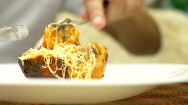 Birisi çatalı tutan pişmiş mantarı kesiyor. Close. Peynir ve yeşillik ile mantar dolması.