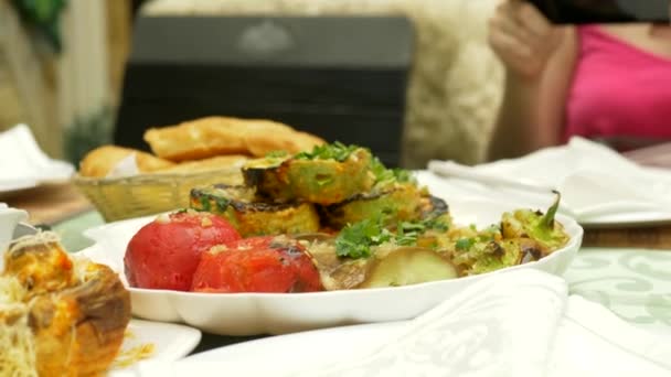 Las manos femeninas hacen fotos en un smartphone en un restaurante con platos de cocina caucásica. verduras a la parrilla, shashlik, salsa — Vídeos de Stock