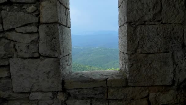 Muro de piedra y ventanas arqueadas con vistas a una cordillera con bosque y neblina sobre las montañas — Vídeos de Stock