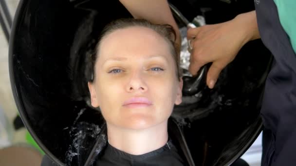 クローズ アップ。そのマスター美容師は、美容院で彼女の髪を洗う女性のクライアントの顔。職場での美容師の概念 — ストック動画