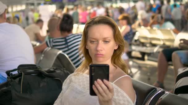 Müde Frau mit Smartphone am Flughafen. Passagierflugzeug in der Flughafenlounge wartet auf einen Flug — Stockvideo