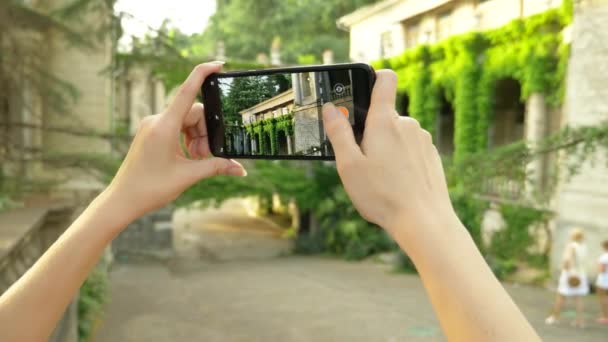 Young woman taking pictures with phone of a colonnade of an old castle — Stock Video