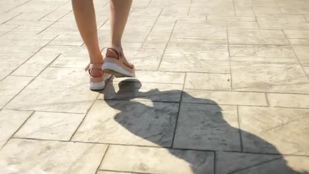 Nohou a pěšky po ulici. Dívky v růžových kožených sandálech na bílé vysoké plošině. Módní koncepce v letní ulici. Nohy a boty — Stock video
