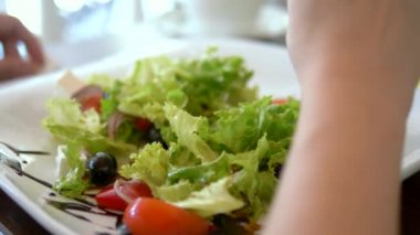 Çatalla kadın ellerinin yakın çekim. Bir kafede lezzetli Yunan salatası yiyen kadın