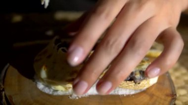 Ahşap bir tahta üzerinde rapana gelen deniz ürünleri julienne. yakın kadın elleri koyu bir arka plan üzerinde, çatal ile bir kabuk bir julienne bir kısmını almak