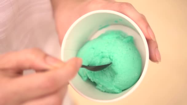 Close-up. Mulher comendo uma deliciosa sobremesa de sorvete de neve azul, com uma colher de um sundae — Vídeo de Stock