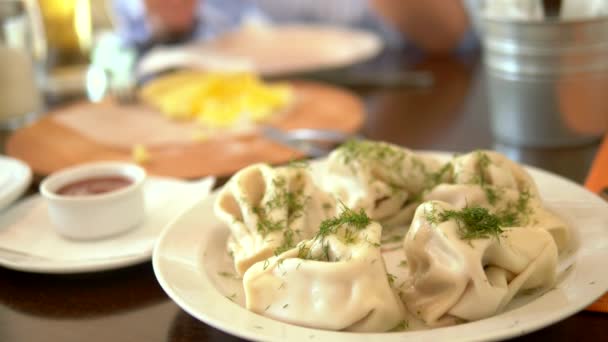 Primo piano, khinkali, un piatto di cucina georgiana, sullo sfondo qualcuno mangia khachapuri Adzhar . — Video Stock