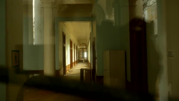 Θέα μέσα από μια κλειστή γυάλινη πόρτα σε ένα μακρύ διάδρομο ενός εγκαταλελειμμένου ξενοδοχείου — Αρχείο Βίντεο
