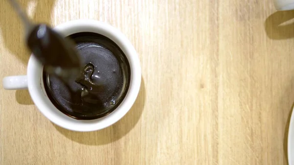 Close-up. Liquid dripping chocolate from a spoon into the cup. hot chocolate in a cafe — Stock Photo, Image