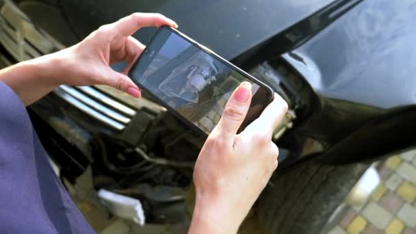 Uma mulher tira uma foto em seu smartphone após o acidente de um pára-choques carro quebrado — Vídeo de Stock
