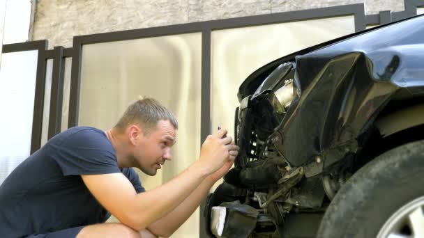 Man neemt een foto op zijn smartphone na een ongeval van een gebroken auto bumper — Stockvideo