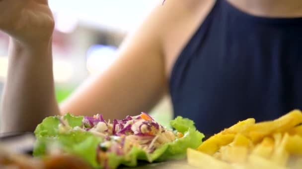 Крупным планом. женщина ест в ресторане быстрого питания гироскопы с салатом из капусты и картошкой фри — стоковое видео