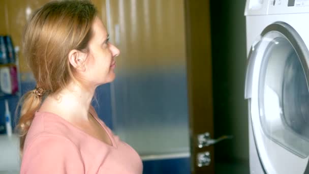 The laundry is dried in a clothes dryer. close-up. woman watching the process of drying clothes in the dryer — Stock Video