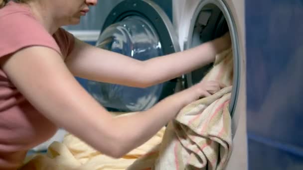 Concept van het wassen thuis. vrouw zet Wasserij in de wasmachine — Stockvideo