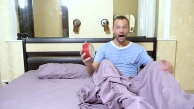 adam sabah uyanır ve o uyuyakta olduğu için sinirlenir. kamera ve çalar saat bakarak ve çığlık