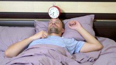 mavi pijama ile adam sabah uyanmak cant, alarmı kapatır