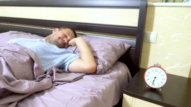 De man in blauwe pyjama wakker in de ochtend en verheugt zich op zijn wakker, schakelt het alarm — Stockvideo