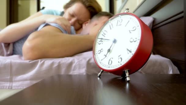 Pareja somnolienta en la cama por la mañana no puede despertar y apaga la alarma — Vídeo de stock