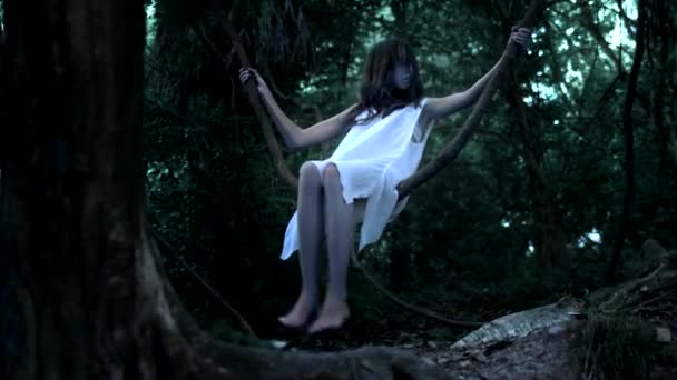 Der Geist eines kleinen Mädchens, eine Fee mit langen brünetten Haaren in einem dichten Märchenwald schwingt auf einer Liane wie auf einer Schaukel — Stockvideo